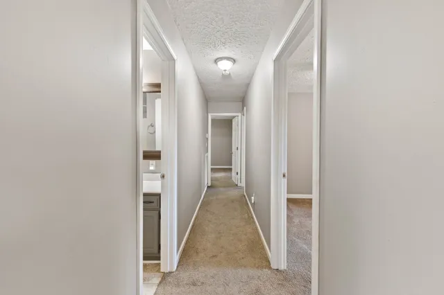 a view of a hallway with wooden floor and a bathroom