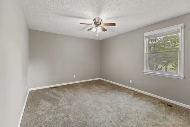 an empty room with windows and ceiling fan