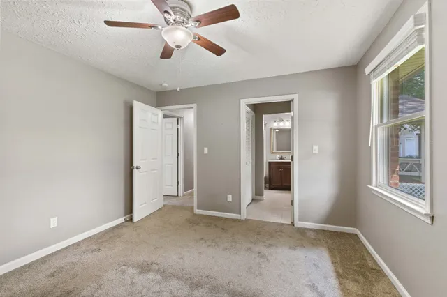 a view of empty room with window and ceiling fan