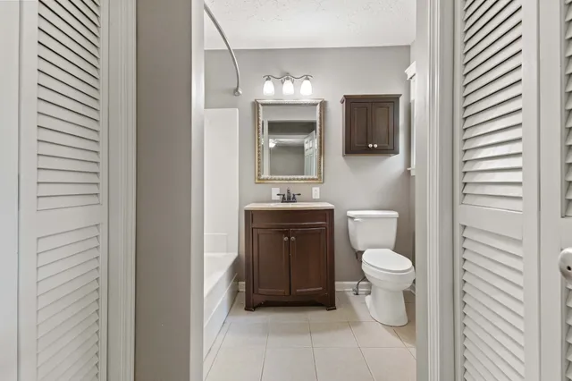 a bathroom with a granite countertop toilet a sink and mirror
