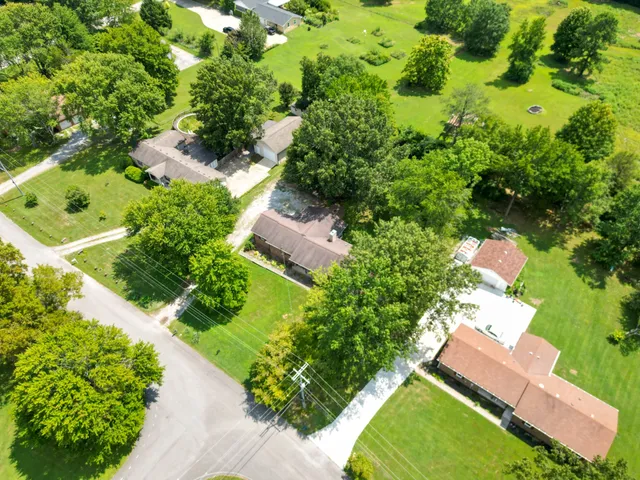 an aerial view of residential house with outdoor space and trees all around
