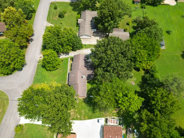 an aerial view of a house with a yard and trees all around
