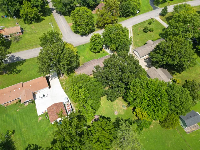 an aerial view of residential house with outdoor space and trees all around