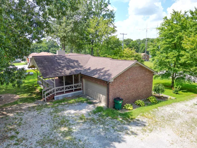 a view of a house with a yard plants and large tree