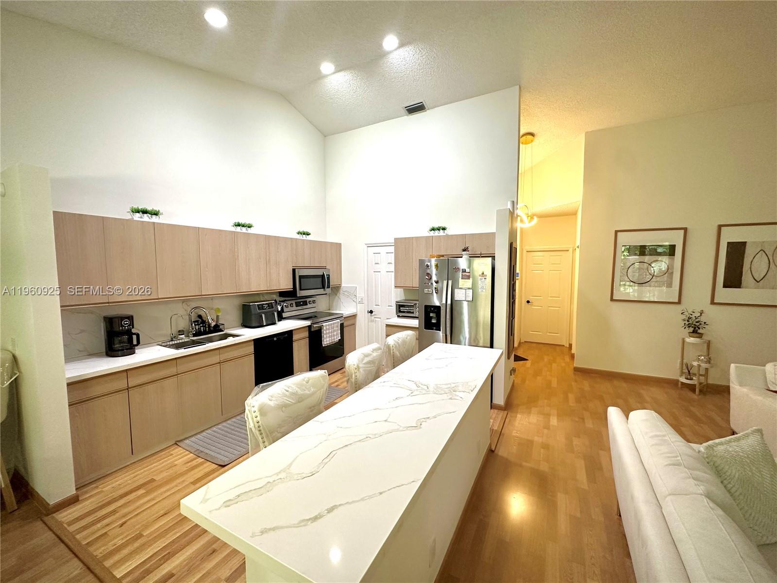 5790 Coach House Circle, Unit E Boca Raton, FL 33486 - Photo 12 of 65 a large kitchen with stainless steel appliances kitchen island a large counter top a stove and a refrigerator