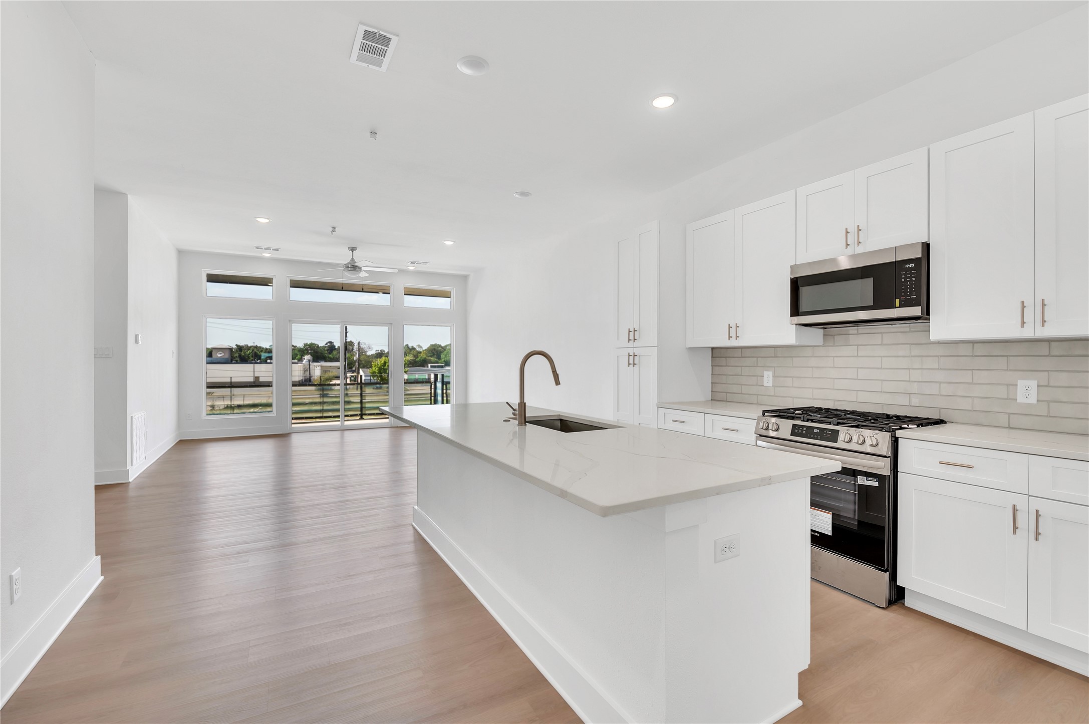 119 Kirby Road, Unit 5205 Seabrook, TX 77586 - Photo 25 of 46 Bright and spacious open-concept kitchen and living area with sleek white cabinetry, modern appliances, and large windows offering abundant natural light and scenic views.