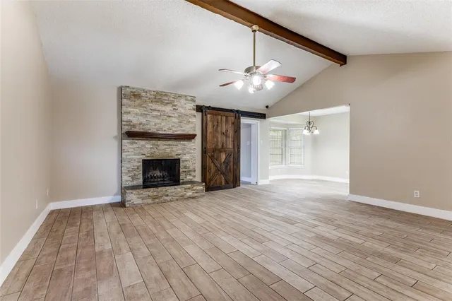 a view of an empty room with wooden floor fireplace and a window