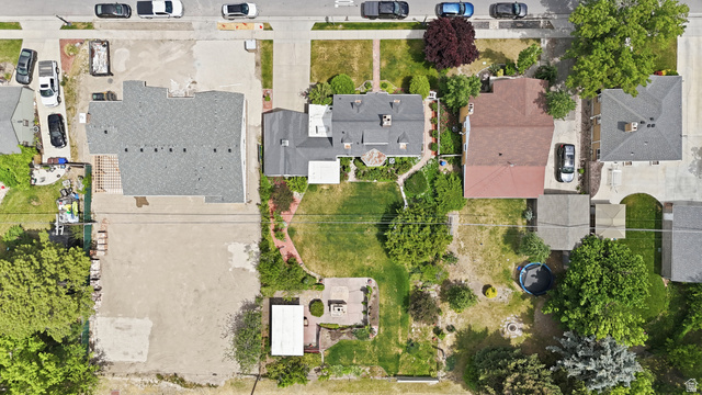 7576 South Jefferson Street Midvale, UT 84047 - Photo 51 of 53 Expansive property featuring a central residence with a dark gray shingle roof, a sizable grassy yard, mature perimeter trees, a paved patio area, and a detached white-roofed structure
