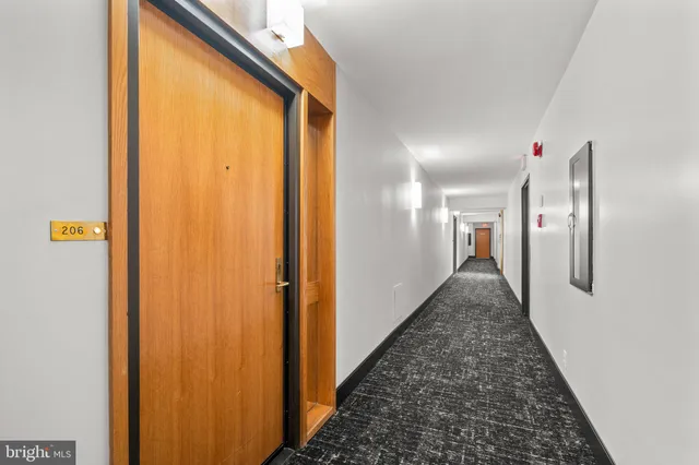 a view of a hallway with wooden floor and a bathroom