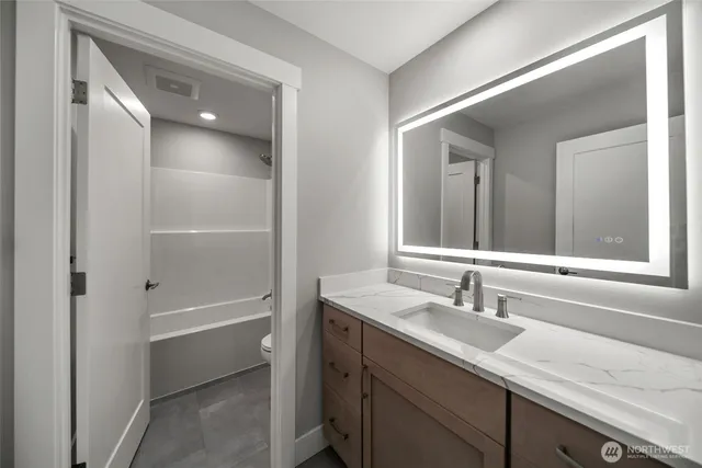 a bathroom with a shower sink vanity and mirror