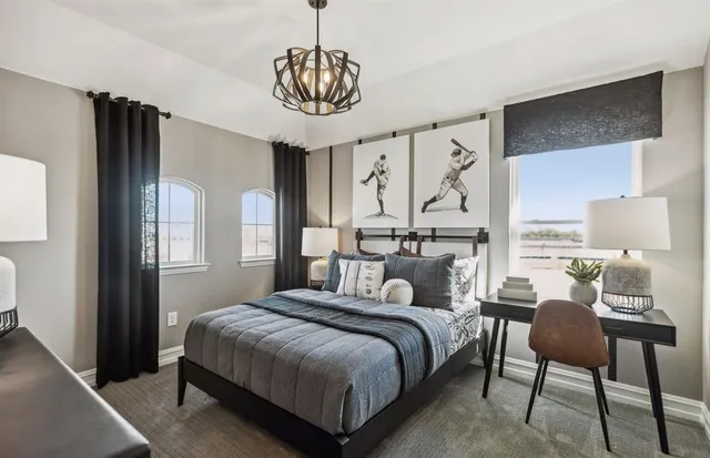 a bedroom with a bed a chandelier and a dresser