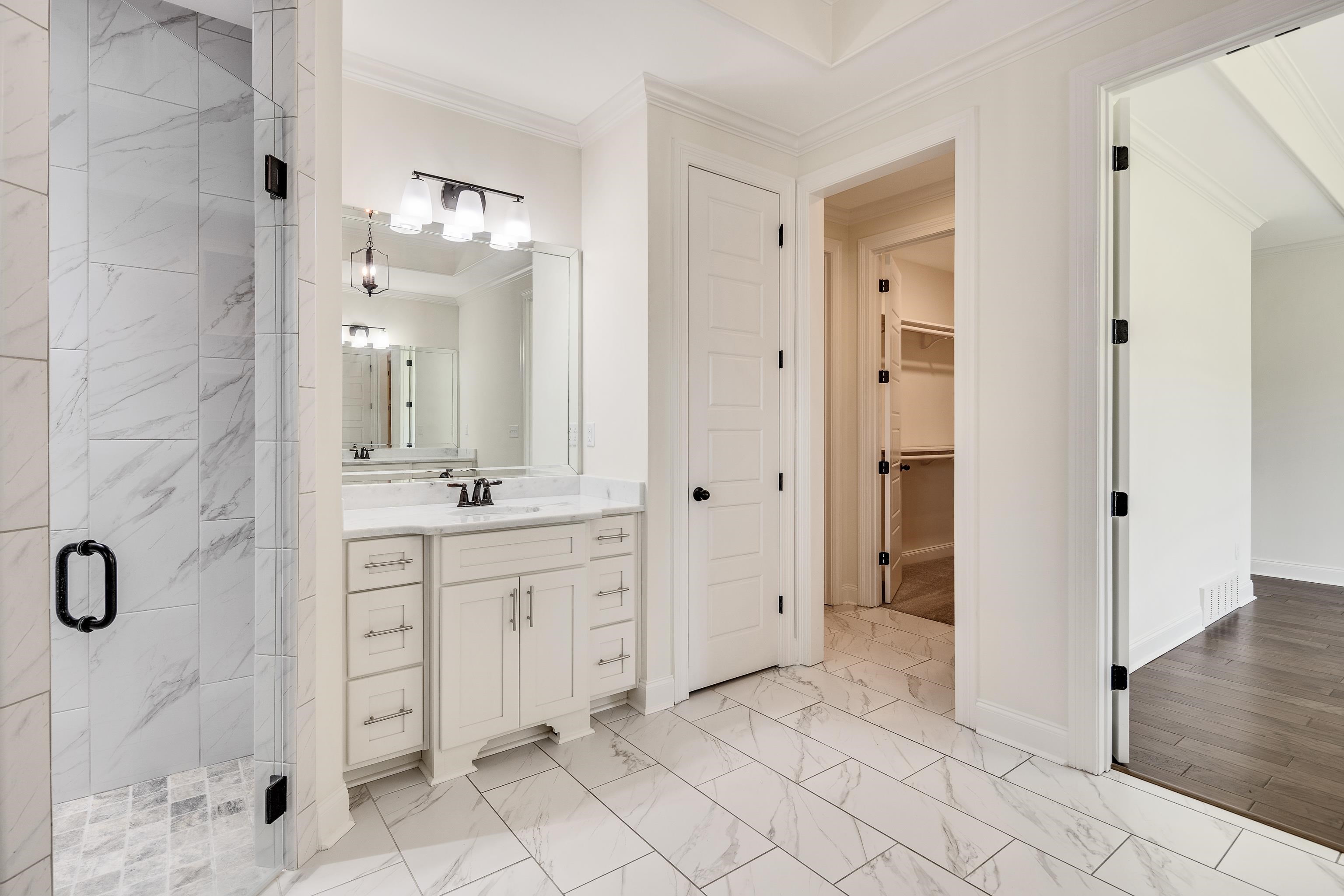 4728 Carousel Lane Collierville, TN 38017 - Photo 19 of 40 Full bathroom featuring a shower stall, marble look tiles, ornamental molding, vanity, and a spacious closet