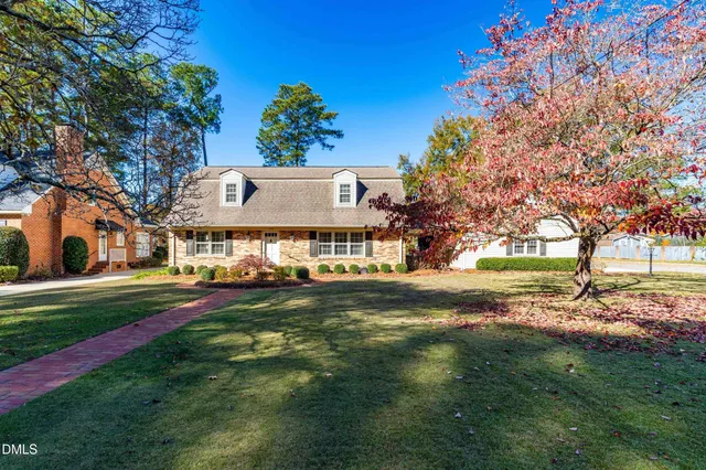 a view of a house with a big yard and large trees