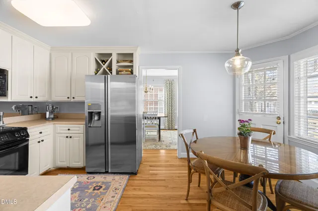 a kitchen with stainless steel appliances granite countertop a dining table chairs stove and refrigerator