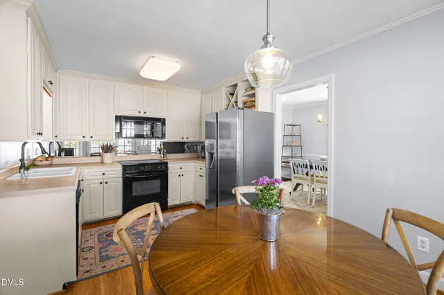 a kitchen with stainless steel appliances kitchen island granite countertop a refrigerator a stove a sink dishwasher a dining table and chairs with wooden floor