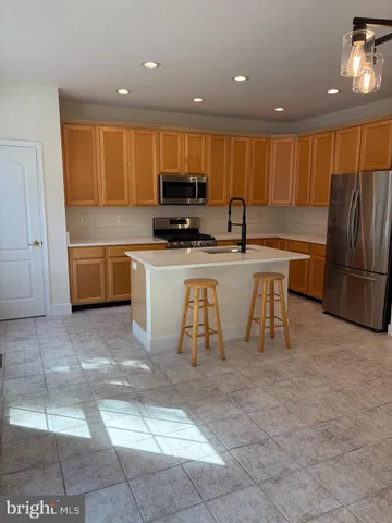 a kitchen with stainless steel appliances a refrigerator a stove a sink a dining table and chairs