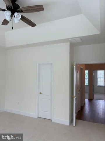 a view of a hallway with wooden floor and a chandelier fan