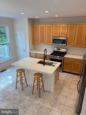 a kitchen with stainless steel appliances a sink a stove a microwave a counter top space cabinets and a window