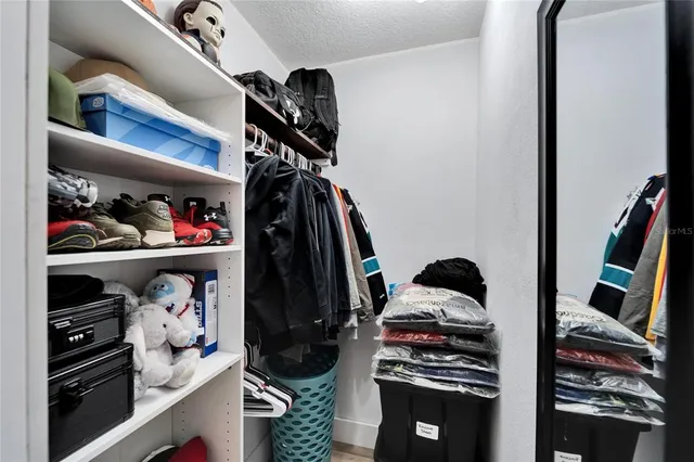 a view of walk in closet with clothes and shoes