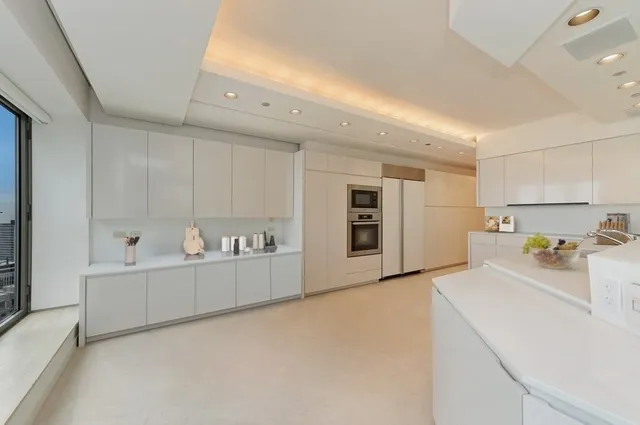 a view of a kitchen with refrigerator and white cabinets
