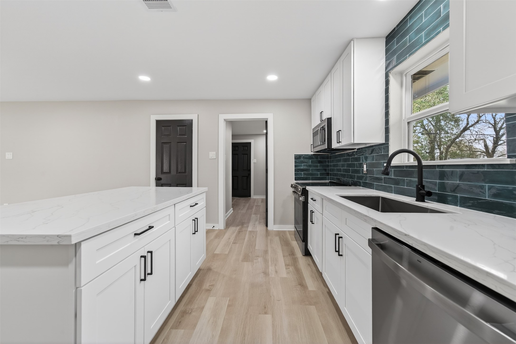 6026 Ridgeway Drive Houston, TX 77033 - Photo 11 of 27 a large white kitchen with a lot of counter space and wooden floor