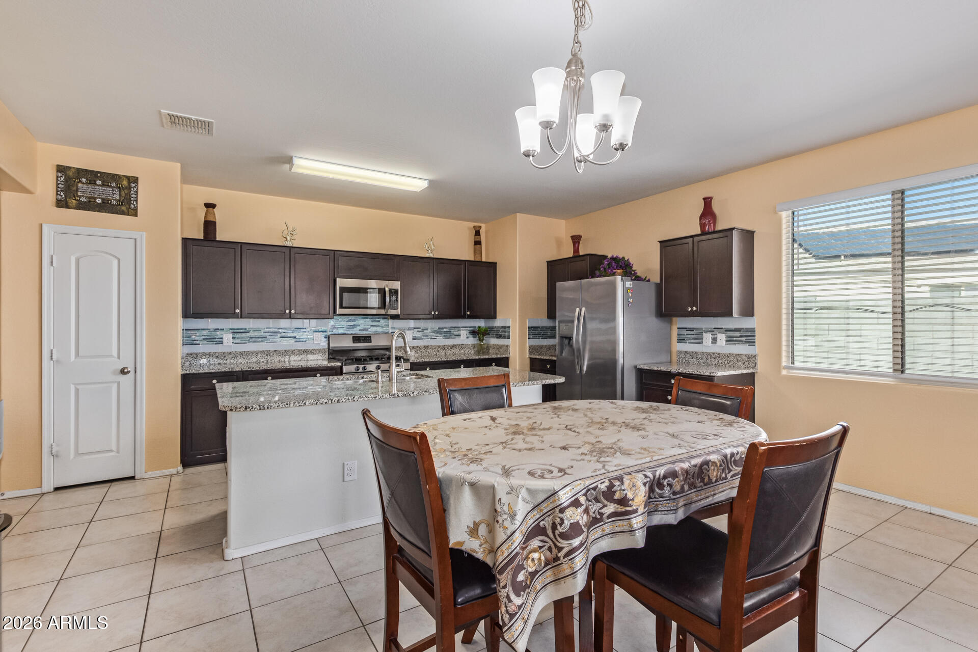 3847 North 308th Lane Buckeye, AZ 85396 - Photo 12 of 32 a view of a dining room with furniture a chandelier and kitchen view