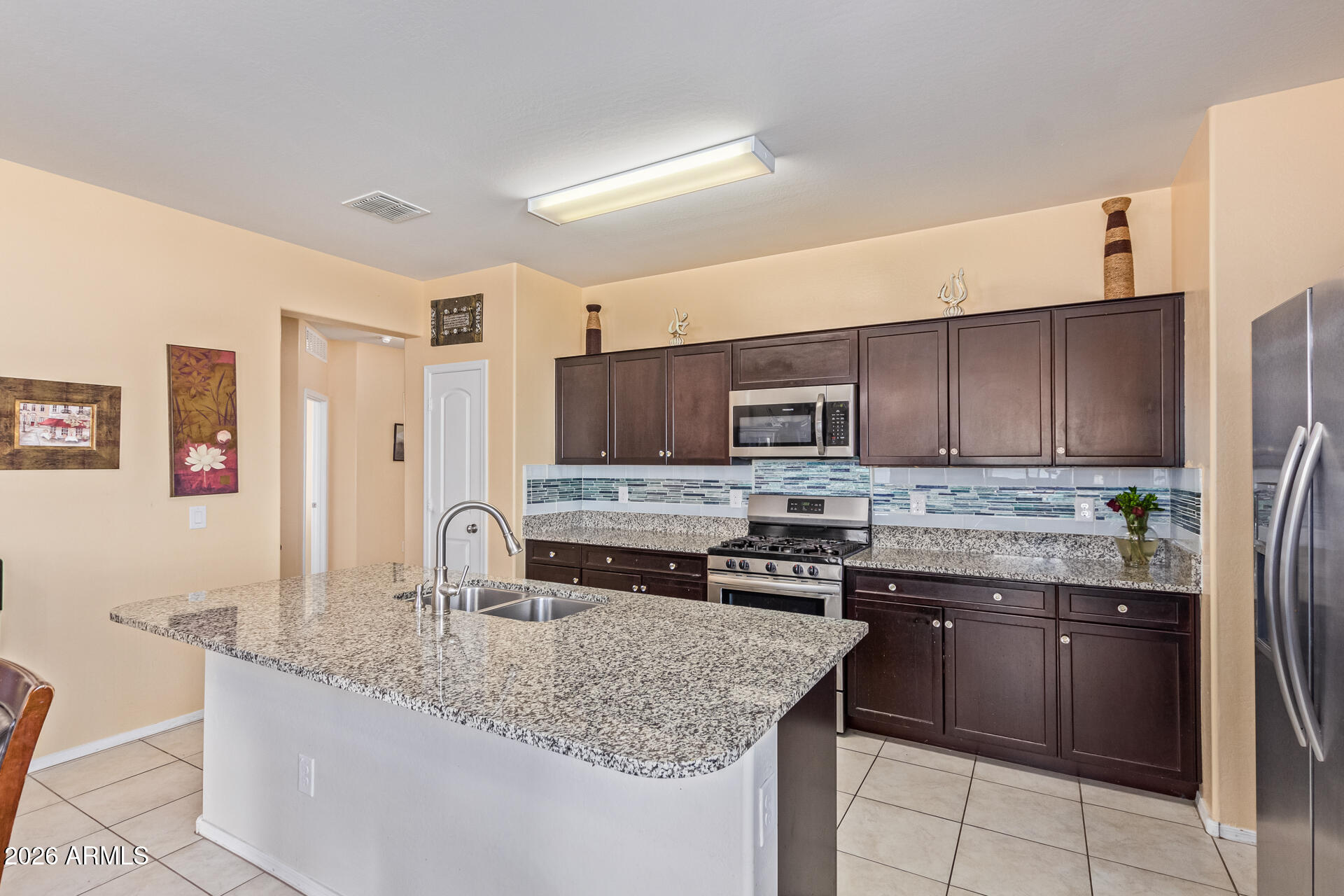 3847 North 308th Lane Buckeye, AZ 85396 - Photo 15 of 32 a kitchen with stainless steel appliances granite countertop a sink stove and refrigerator