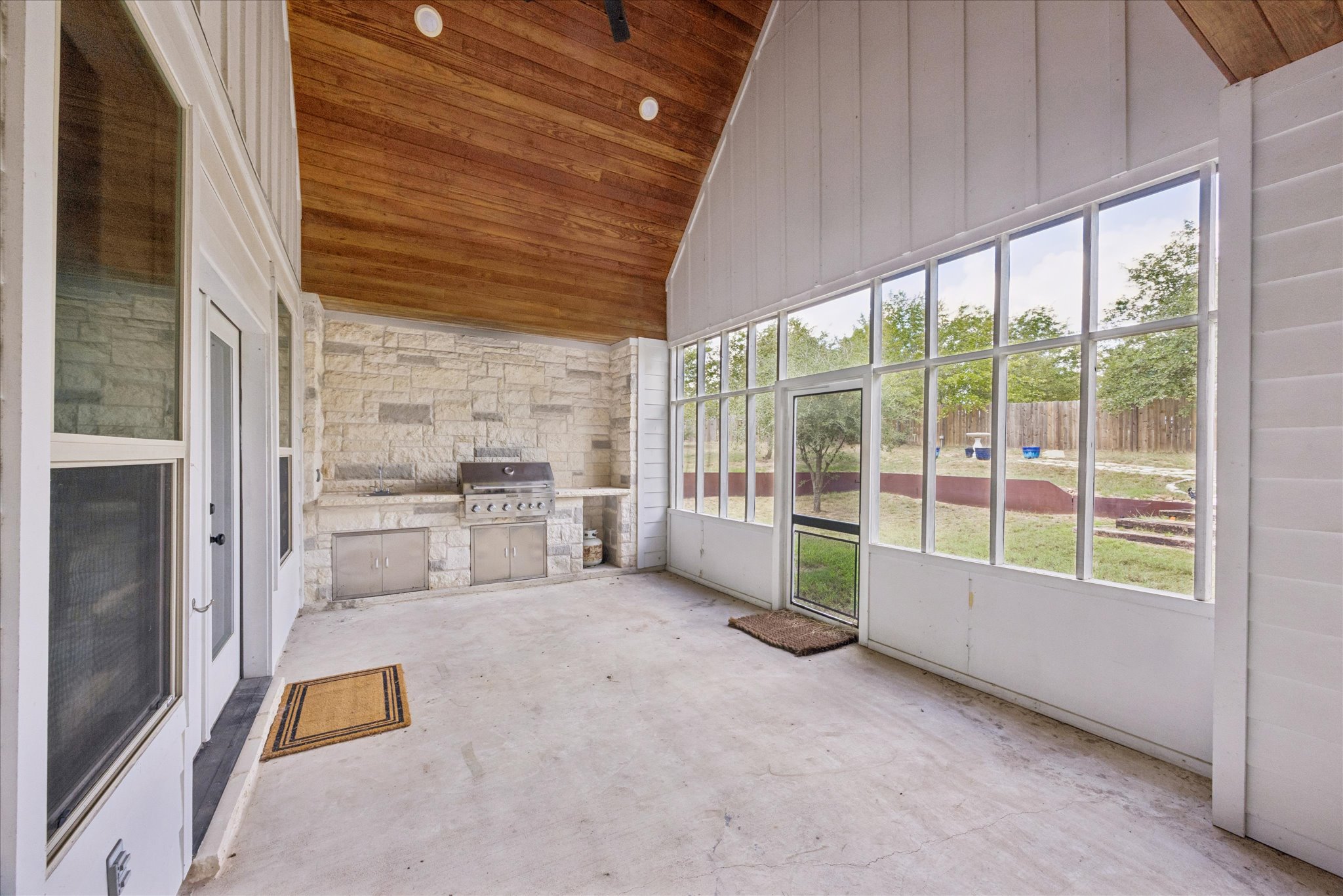 116 Mallard Road Bastrop, TX 78602 - Photo 26 of 31 A vaulted wood ceiling and stone outdoor kitchen highlight this screened back porch.