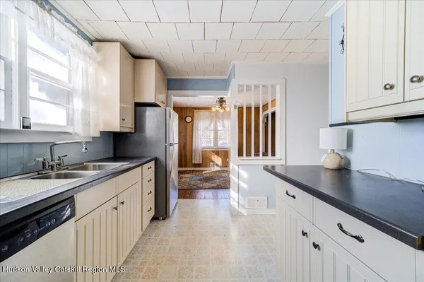 a kitchen with a sink dishwasher a stove and white cabinets with wooden floor