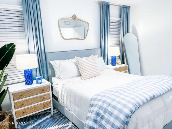 a bedroom with a bed and a large mirror next to a window