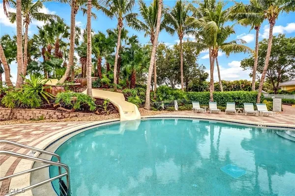 a view of pool with lawn chairs and plants