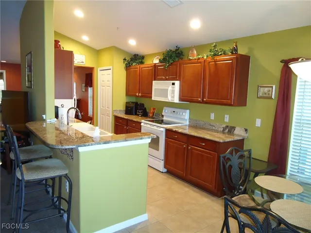 a kitchen with kitchen island a stove a sink a refrigerator and chairs