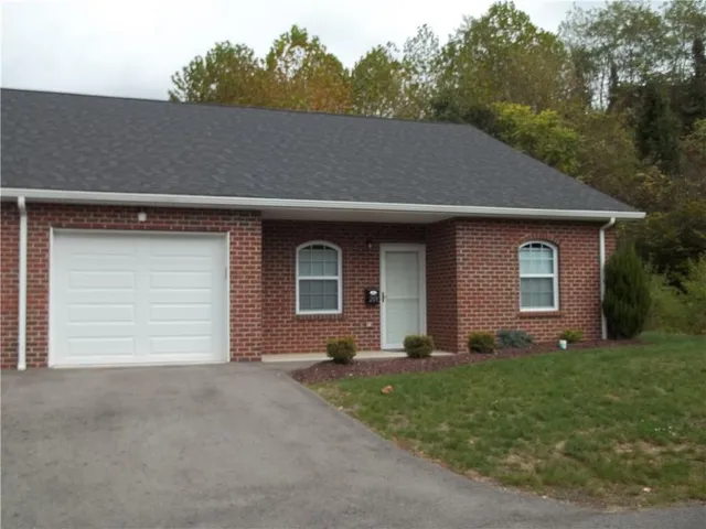 a front view of house with yard and trees in the background