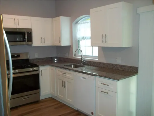 a kitchen with granite countertop white cabinets stainless steel appliances and a sink