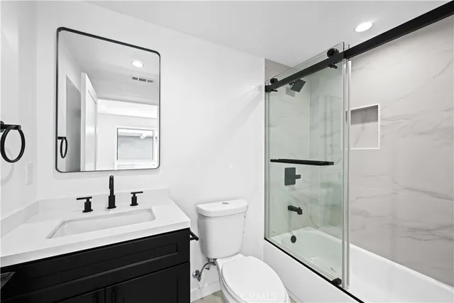 a bathroom with a bathtub shower sink vanity and toilet