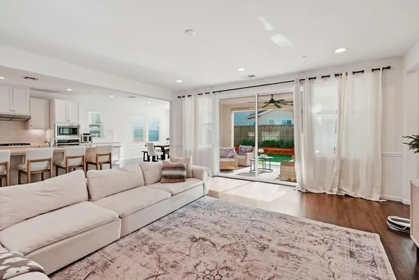 a large kitchen with kitchen island a stove a sink a refrigerator and white cabinets with wooden floor