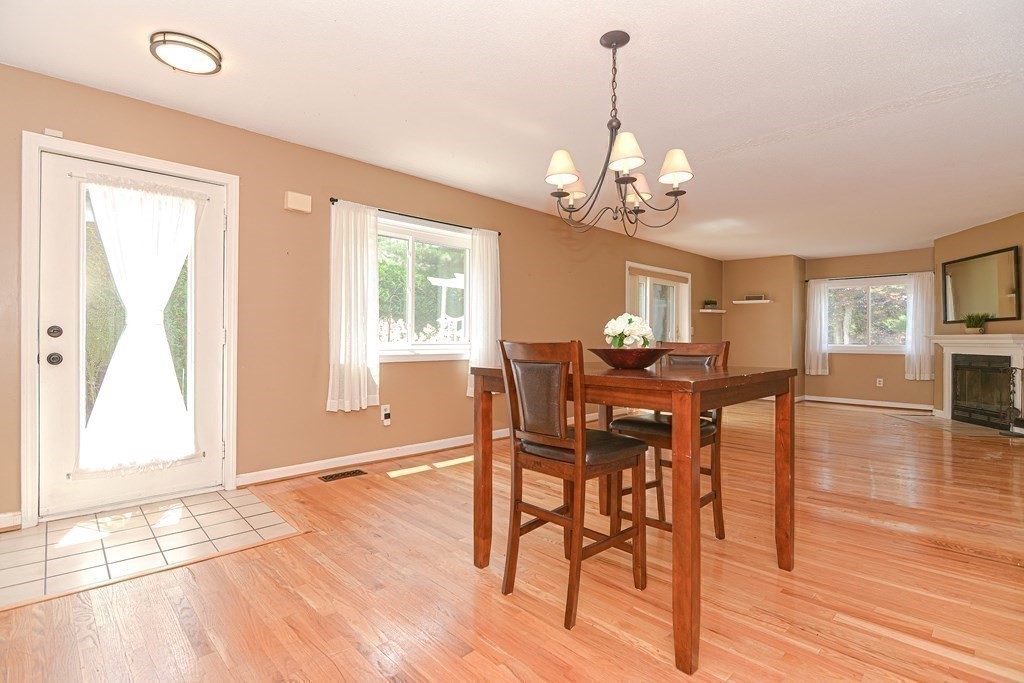 9 Crown's Way, Unit 9 Uxbridge, MA 01569 - Photo 12 of 40 a dining room with wooden floor a chandelier a wooden table and chairs