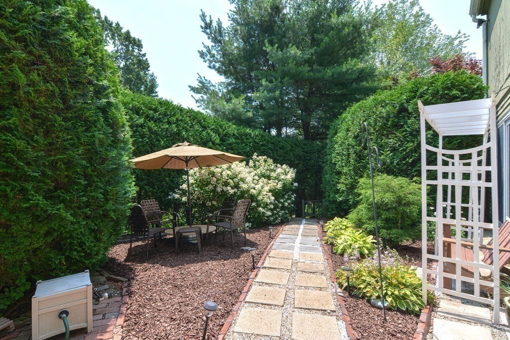 9 Crown's Way, Unit 9 Uxbridge, MA 01569 - Photo 28 of 40 a view of a patio with table and chairs potted plants with large trees