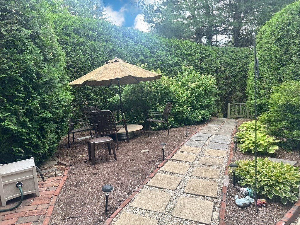 9 Crown's Way, Unit 9 Uxbridge, MA 01569 - Photo 32 of 40 a backyard of a house with table and chairs under an umbrella