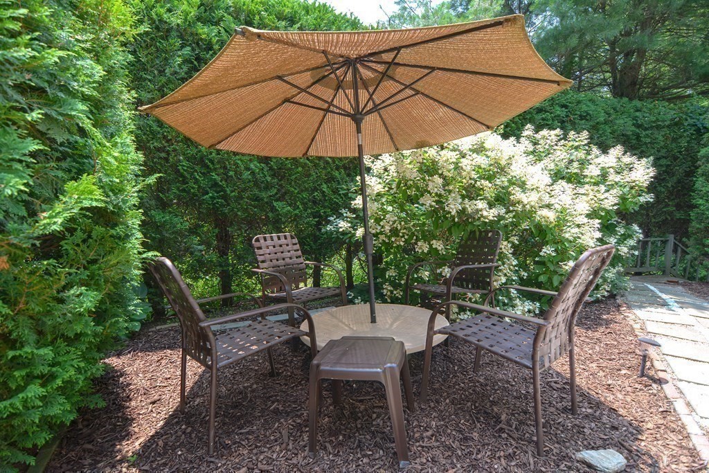 9 Crown's Way, Unit 9 Uxbridge, MA 01569 - Photo 34 of 40 a backyard of a house with table and chairs under an umbrella