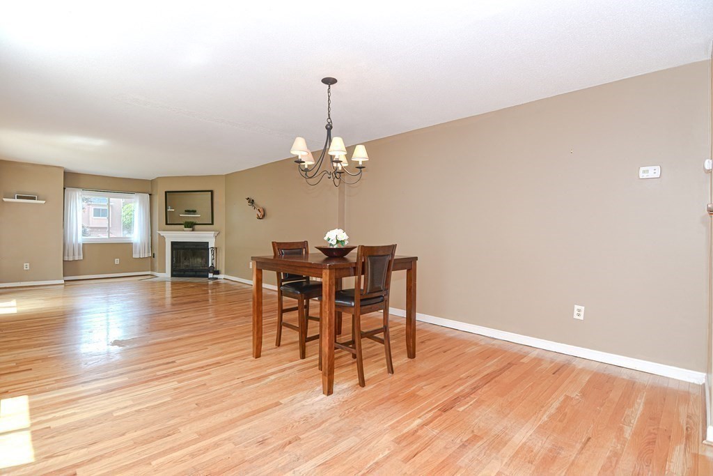 9 Crown's Way, Unit 9 Uxbridge, MA 01569 - Photo 9 of 40 a dining room with wooden floor a chandelier a wooden table and chairs