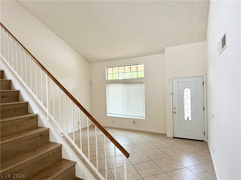135 Primero Way Henderson, NV 89074 - Photo 4 of 15 Enter into a bright, open space featuring a prominent staircase and tiled flooring.