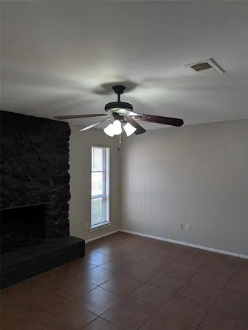 a view of an empty room with window and chandelier fan