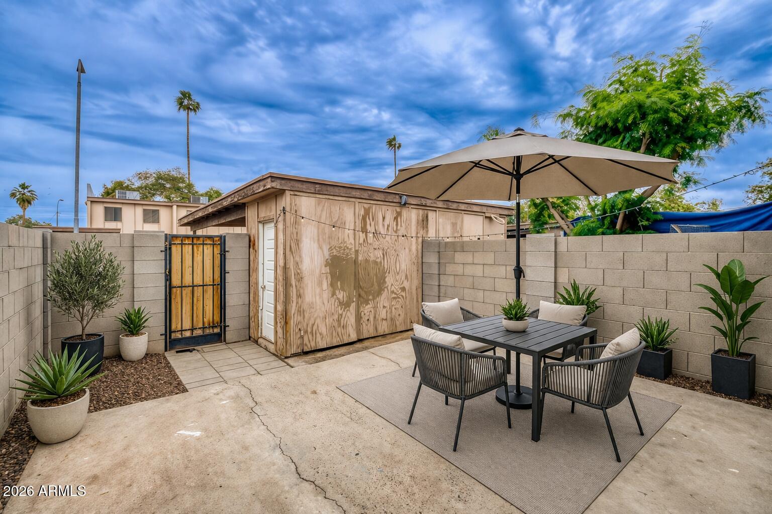 4625 West Thomas Road, Unit 39 Phoenix, AZ 85031 - Photo 16 of 27 a patio with a table and chairs under an umbrella