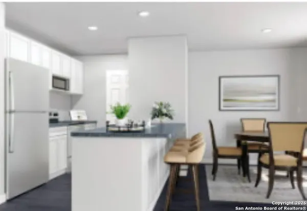 a kitchen with stainless steel appliances granite countertop a dining table chairs and a refrigerator