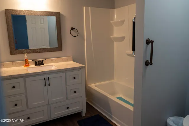 a bathroom with a tub sink and mirror