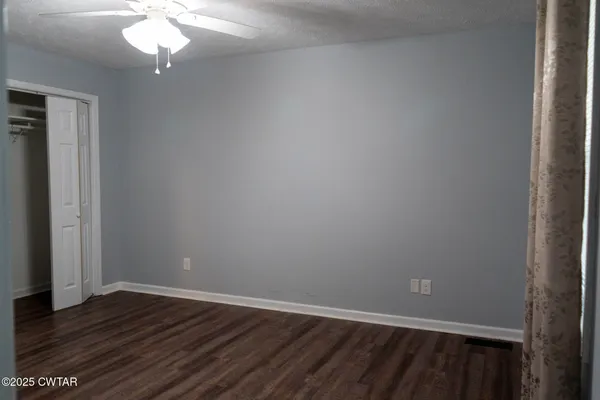 a view of a room with wooden floor and chandelier fan