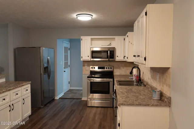 a kitchen with stainless steel appliances kitchen island granite countertop a stove a sink and a refrigerator