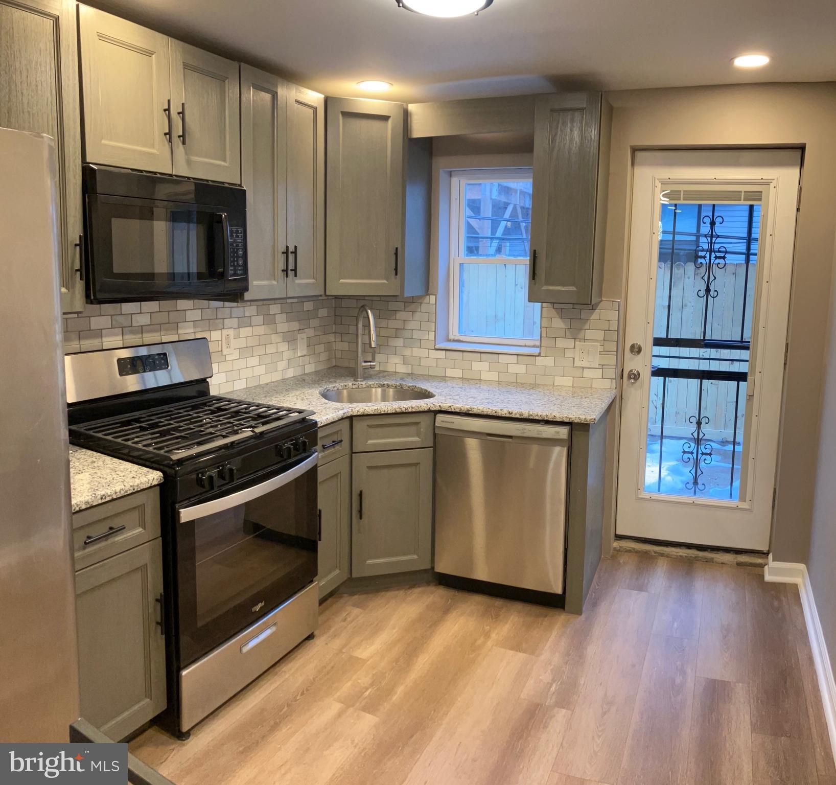 2625 Manton Street Philadelphia, PA 19146 - Photo 4 of 25 a kitchen with granite countertop a stove top oven a sink dishwasher and a microwave oven with wooden floor
