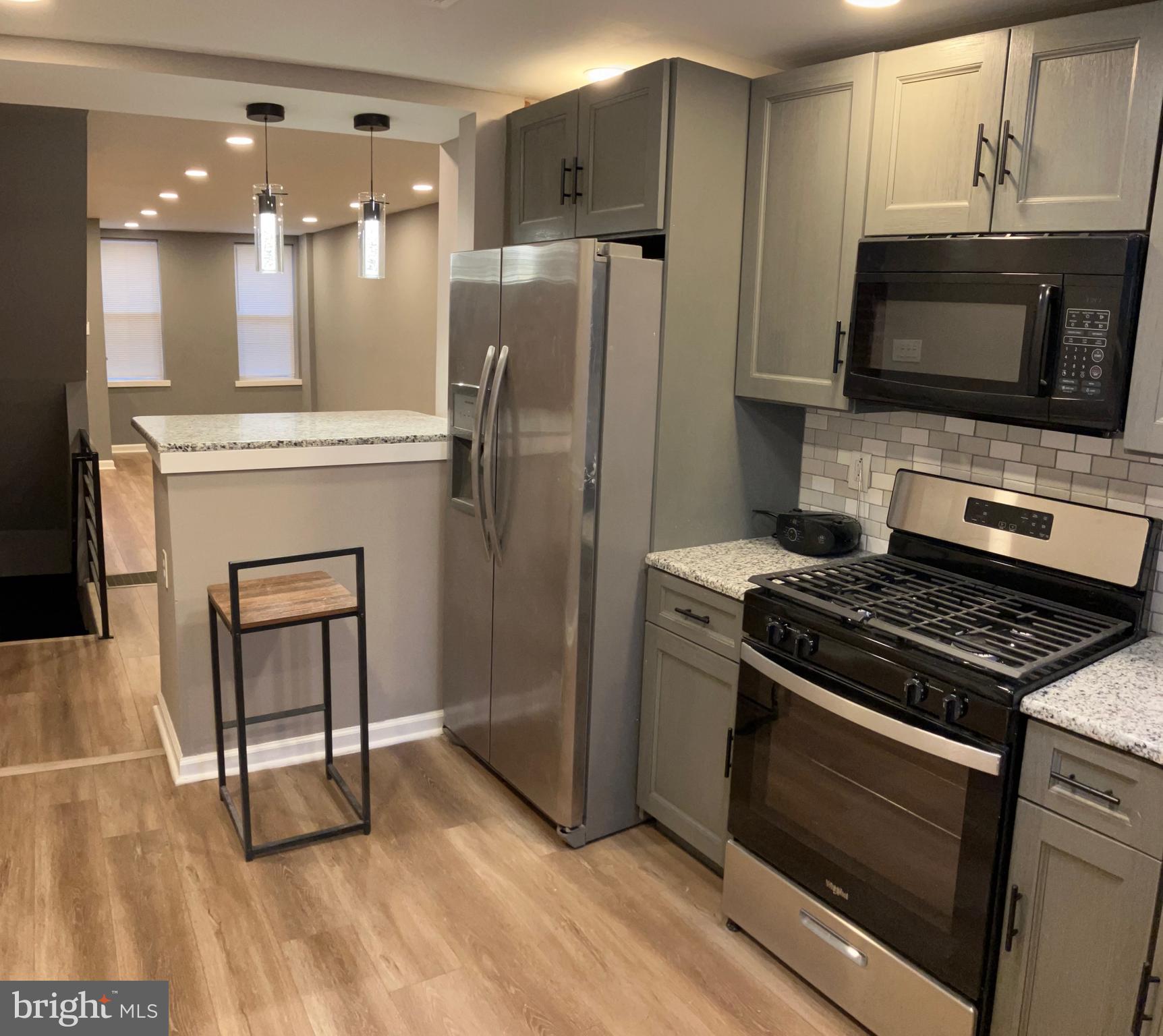 2625 Manton Street Philadelphia, PA 19146 - Photo 6 of 25 a kitchen with granite countertop a stove a microwave a refrigerator a sink and a dining table with wooden floor